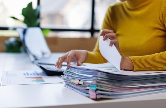 Business asian woman hands working in Stacks of paper files for searching and checking unfinished document achieves on folders papers at busy work desk office

