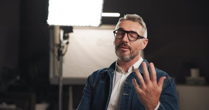 Talkshow, interview and man on set for filming with documentary, press or movie in studio. Recording, discussion and male journalist by lights for television public speaking with production equipment