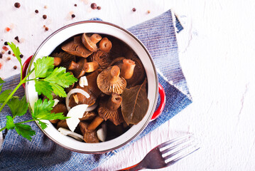 Pickled mushrooms in a metal bowl. Marinated mushrooms with pepper and bay leaf.