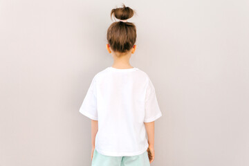 The girl is wearing a white blank T-shirt. Stylish cute girl. Template for design, copy space for logo, text. Back view. Mockup..