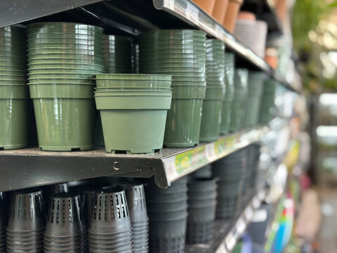 Stacks of green plastic flower pots on a store shelf.
