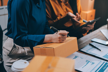 Asian SME business women use laptop computer checking customer order online shipping boxes at home....