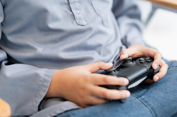 child holding black gaming controller, focused on playing video games. casual setting highlights...