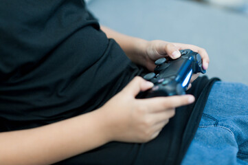 child playing video games with black game controller, focused and engaged. setting is casual,...