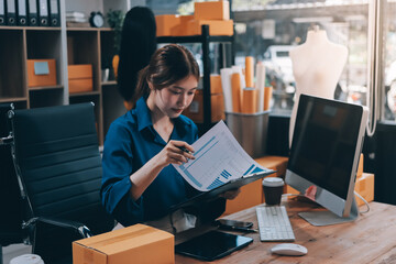 Asian SME business women use laptop computer checking customer order online shipping boxes at home....