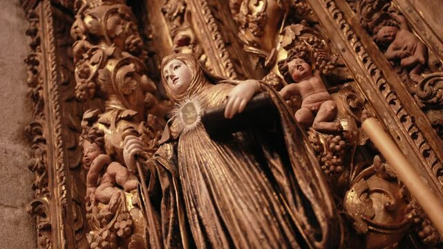 Low angle close up of a gilded religious statue holding a monstrance and book in ornate altar
