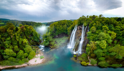 Fototapeta premium Majestic Waterfalls and Lush Greenery: A stunning view of cascading waterfalls amidst a vibrant expanse of verdant trees. Capturing the serenity and beauty of untouched wilderness.