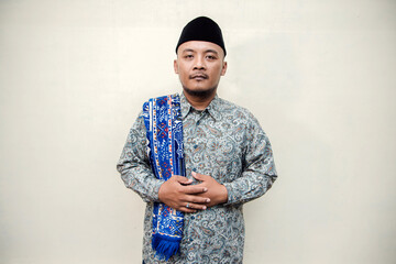 Muslim themed isolated concept photo of a tanned Asian man wearing a paisley or batik patterned...