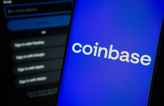 Dhaka, Bangladesh- 05 March 2025: Coinbase logo is displayed on a smartphone screen, with the coinbase login page visible on a computer screen in the background.