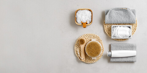 Spa, wellness, bath products as minimal style aesthetic banner, magnesium salt flakes, folded grey towels, natural brushes, massagers, reusable pads, gray background, top view lifestyle content