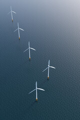 wind turbines lined up in the sea under a clear sky. Vertical aerial shot. © piyaset