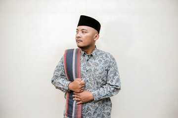 Muslim themed isolated concept photo of a tanned Asian man wearing a paisley or batik patterned...