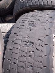 A close-up of a several damaged tire with deep cracks and missing tread, indicating extreme wear...