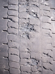 A close-up of a several damaged tire with deep cracks and missing tread, indicating extreme wear...