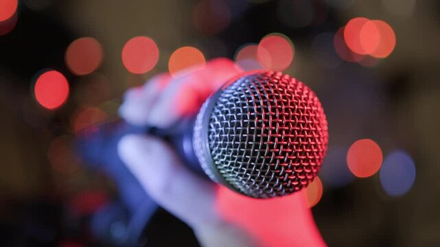 Soloist takes microphone with hand, checking sound by tapping finger before start of performance, close-up.