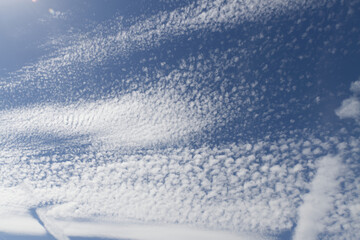blue sky with linear clouds, blue sky clouds, strange cloud cover, small circular formations in the sky, white haze in the air, sheep clouds
