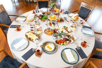 Classic Turkish breakfast in luxury restaurant. Delicious Turkish breakfast served on a round table with fried eggs, fruits, vegetables and drinks. Wide angle photo.Turkey.