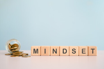 For business mindset concept, MINDSET text on wooden cube blocks with blurred coins in jar including copy space
