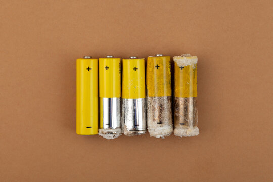 Old used batteries with varying degrees of deterioration and damage. Oxidized and leaked alkaline batteries LR6 type or AA. Problems of electronic waste recycling and separate collection garbage