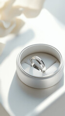 Silver ring in a white ring box with a flower in the background