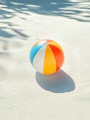 Obraz premium Colorful Beach Ball on Sandy Shore: A vibrant beach ball rests on soft sand, casting a playful shadow, hinting at sunny days and carefree moments.