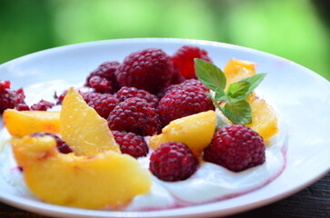 delicious healthy dessert for diet low calorie peach raspberries with cream or yogurt soft cottage cheese Summer oatmeal with raspberries, peaches and nuts in white bowl, top view. Healthy vegetarian 
