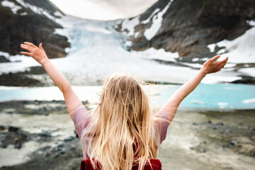 Woman tourist traveling solo in Norway enjoying Steindalsbreen glacier view summer vacations...
