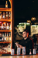 Bartender Polishing Glassware in Stylish Bar with Shelves of Whiskey Bottles