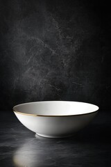 Elegant white ceramic bowl with gold rim on dark marble surface
