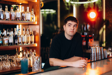 Man Relaxing at a Bar Counter with Various Bottles in the Background