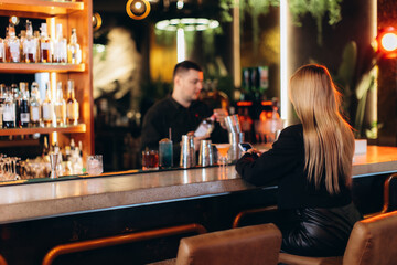 Woman Sitting at Stylish Bar While Bartender Prepares a Drink