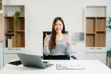 Young attractive Asian woman smiling thinking planning writing in notebook, tablet and laptop working from home