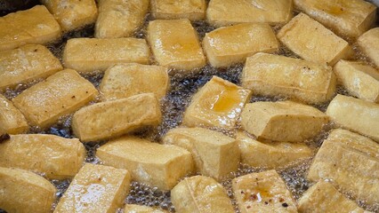 Close up, Golden crispy tofu frying in bubbling hot oil