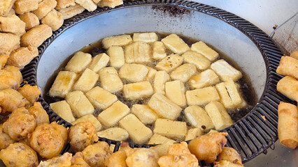 Golden crispy tofu frying in bubbling hot oil