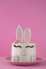 Easter bunny celebration cake on a plate on a pink background. Funny food idea. Copy space.