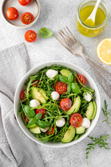 Fresh salad with arugula, mozzarella, tomatoes and avocado in a bowl. Healthy vegetarian dish.