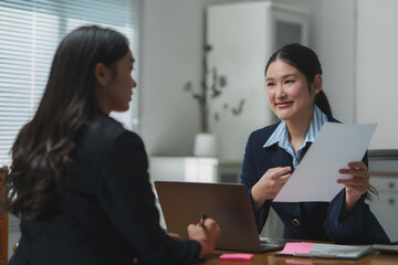 Two businesswomen discussing contract in modern office