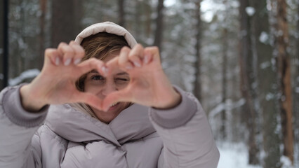 Young pretty woman in warm winter clothes walking in snowy park