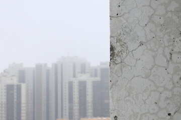 Fragment of an unrepaired wall and a blurred background on the left with silhouettes of houses in the distance for text or insertion