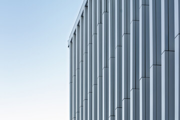Close-up of a high-rise facade with repeating vertical panels forming a dynamic geometric pattern. Minimalist urban design.