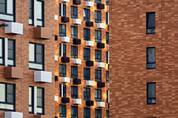 Modern residential buildings with brick facades and a rhythmic arrangement of windows create an abstract geometric pattern in the urban space.