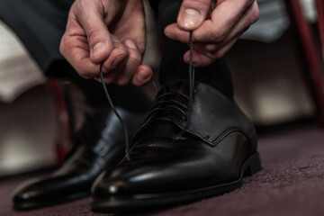 Man tying black formal shoes, getting ready