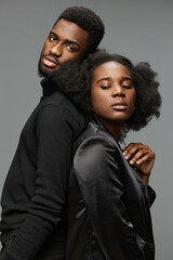 Elegant portrait of a Black couple with stylish attire, showcasing intimacy and sophistication against a grey background, perfect for romantic or fashion themed projects