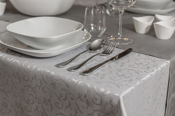 Elegant table setting with white patterned tablecloth