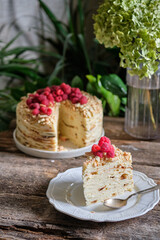 Piece of Napoleon cake with raspberry on a wooden background. Side view.