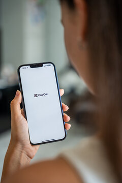 Prague, Czech republic - May 2, 2024: Woman holding iPhone with logo of application CapCut on the screen, using mobile application for business home