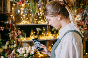 A woman in her florist shop collects bouquets of flowers. The concept of a small business. Bouquets of tulips for the holiday on March 8.