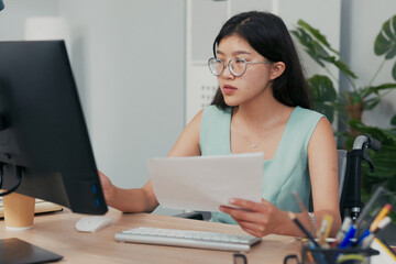 Disabled woman works in accounting, insurance, in a company as a secretary, checks documents,...