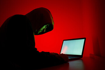 Individual Engaged in Coding Activity With Laptop Under Red Lighting at Night