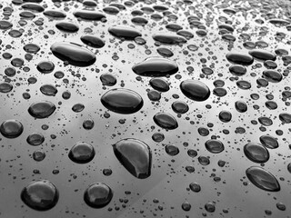 Big rain drops on the metal surface with sky reflection. After rain background